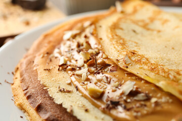 Plate of crepes with peanut butter and nuts, close up
