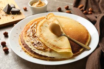Concept of breakfast with crepes with peanut butter and nuts on gray table