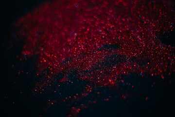 Red sand from sequins. Scattered sparkles on a black background. Space texture. Stars