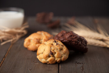 Cookies on a wooden table with a glass of milk and wheat ear