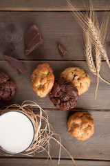 Cookies on a wooden table with a glass of milk and wheat ear