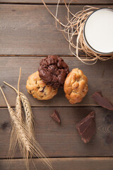 Cookies on a wooden table with a glass of milk and wheat ear