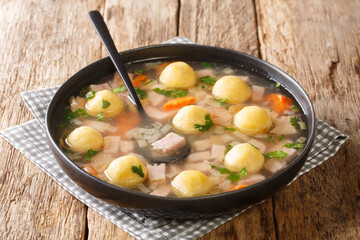 Homemade fresh soup with ham, vegetables and cornmeal dumplings close-up in a plate on the table. horizontal
