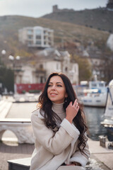 Obraz premium A woman in beige clothing enjoying the view of the sea on a warm, windy day.