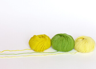 Three skeins of yarn for hand knitting: green and two shades of yellow color on white background....