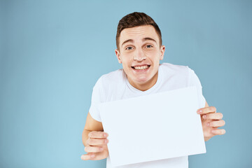 man holding a sheet of paper in his hands white t-shirt cropped view blue background