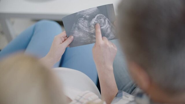 Man and woman looking at pregnancy scan together, preparation for parenthood