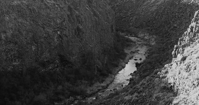 Black and white video of crooked river at the bottom of a canyon in Oregon 