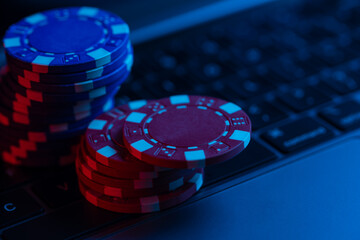 poker chips on keyboard concept of online casino game red and blue neon light