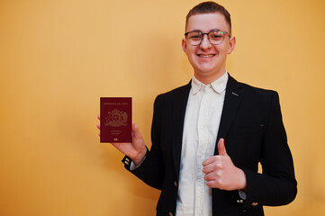 Young handsome man holding Republic of Chile passport id over yellow background, happy and show...