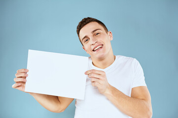 man holding a sheet of paper in his hands white t-shirt cropped view blue background