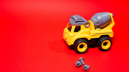 Obraz premium Toy on a red background. A boy's car with a place for text for a toy store. Disassembled typewriter on screws with screwdriver
