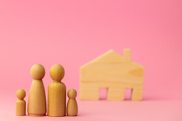 Wooden house miniature and toy people on pink background
