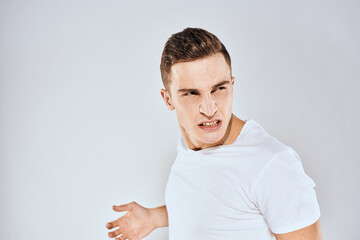 Fototapeta premium Man in white t-shirt displeased facial expression gesturing with hands studio lifestyle