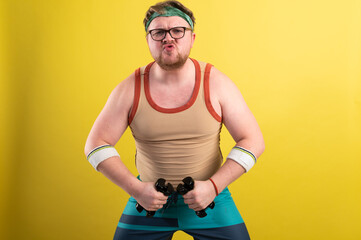 funny fat man doing exercises with dumbbells. Overweight. yellow background