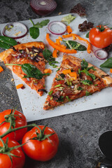 Homemade Italian pizza with bell peppers, tomatoes, cheese, onions and herbs, on light baking paper