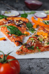 Homemade Italian pizza with bell peppers, tomatoes, cheese, onions and herbs, on light baking paper