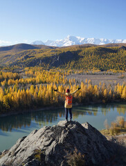 Fototapeta na wymiar Traveler Hands Raising and Looking at the Golden Autumn in Altai Mountains, Siberia, Russia.