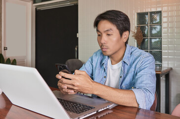 Zoom View Front Left Asian Casual Businessman in Denim or Jeans Shirt Using Smartphone for Online Chat in Coffee Shop. Casual Businessman with Technology