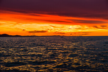 Background with landscape of sunset over sea with reflection in the water and dramatic sky, view from beach in Zadar, Dalmatia, Croatia, Europe