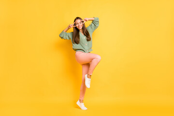 Full size photo of young lovely pretty attractive happy funky smiling girl show v-sign isolated on yellow color background