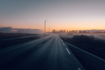 Rural country road on a foggy morning at sunrise.