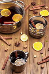Citrus mulled wine with spices in metal mugs and saucepan