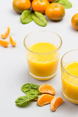 Citrus fruit juice in glasses. Tangerine slices with leaves on table