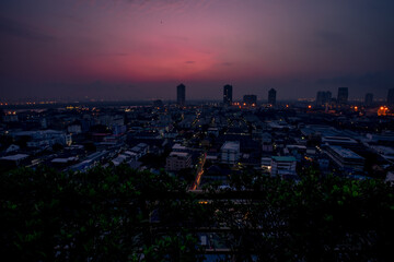 Obraz premium The high angle background of the city view with the secret light of the evening, blurring of night lights, showing the distribution of condominiums, dense homes in the capital community