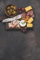 Fototapeta na wymiar Variety of meat, cheese snacks, olives, grapes and nuts for wine. Dark background with copy space