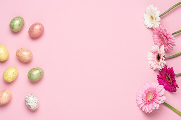 Happy Easter holiday pink background. Flat lay colourful decorated eggs and flowers. Design pastel tone