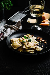 Ravioli with spinach, ricotta and parmesan on a black plate