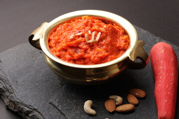 Gajar ka halwa is a carrot-based sweet dessert pudding from India. Garnished with Cashew almond nuts and Served in brass bowl.
