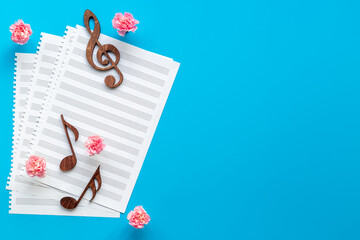 Musical wooden notes on music sheet with flowers. Top view
