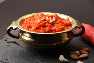 Gajar ka halwa is a carrot-based sweet dessert pudding from India. Garnished with Cashew almond nuts and Served in brass bowl.