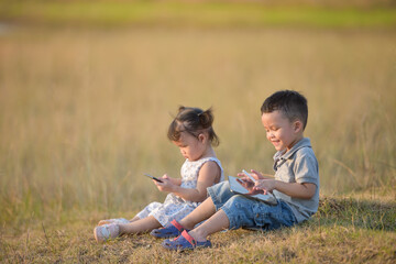 Child With Tablet.Happy siblings lying outdoor and playing with pc tablet together.