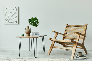 Minimalist concept of living room interior with rattan armchair, walnut coffee table, tropical leaf in vase, clock, mock up painintgs, books and personal accessories in stylish home decor. Template.