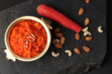Gajar ka halwa is a carrot-based sweet dessert pudding from India. Garnished with Cashew almond nuts and Served in brass bowl.