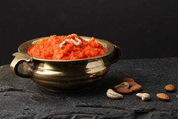Gajar ka halwa is a carrot-based sweet dessert pudding from India. Garnished with Cashew almond nuts and Served in brass bowl.