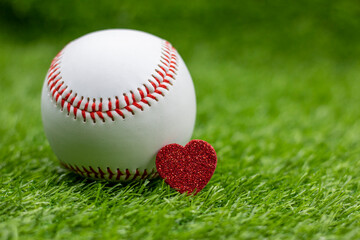 Baseball with red heart are on green grass with love for Valentine's Day