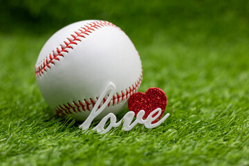 Baseball with red heart are on green grass with love for Valentine's Day