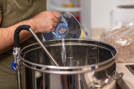 A Man Fills The Kettle With Water To Make Beer