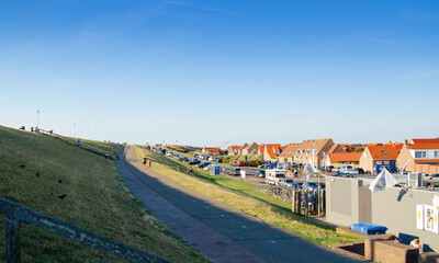 Fototapeta na wymiar Westkapelle, The Netherlands, August 2019. The built-up area, below sea level, is protected by an artificial hill that surrounds it. On the top of the hill a red road.