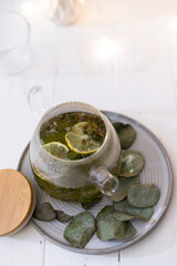 Teapot of herbal tea with lemon on blurred light background