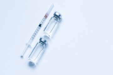 Two glass bottles with liquid and syringe on gray background with copy space. The medical conception of combating the covid-19 pandemic. Flu vaccination.  Flat lay