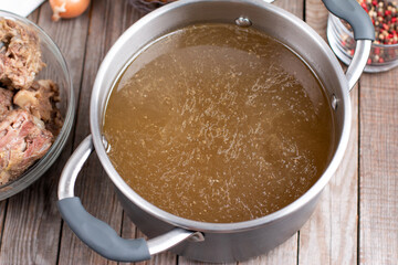 Bone Broth Bouillon in Metal saucepan on the table, paleo diet