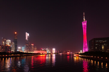 Glowing the Canton Tower and skyscrapers stands on the banks of the Pearl River in Guangzhou in the evening. China