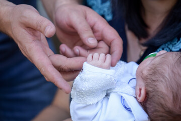 Parents hold the newborn's hand. The little hand of the baby is holding the father's finger. A family. Close-up.