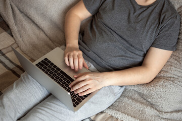 A man works for a notbook lying on the bed