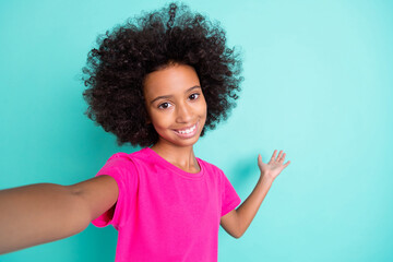 Photo portrait of afro american girl showing blank space with one hand taking selfie isolated on vivid cyan colored background